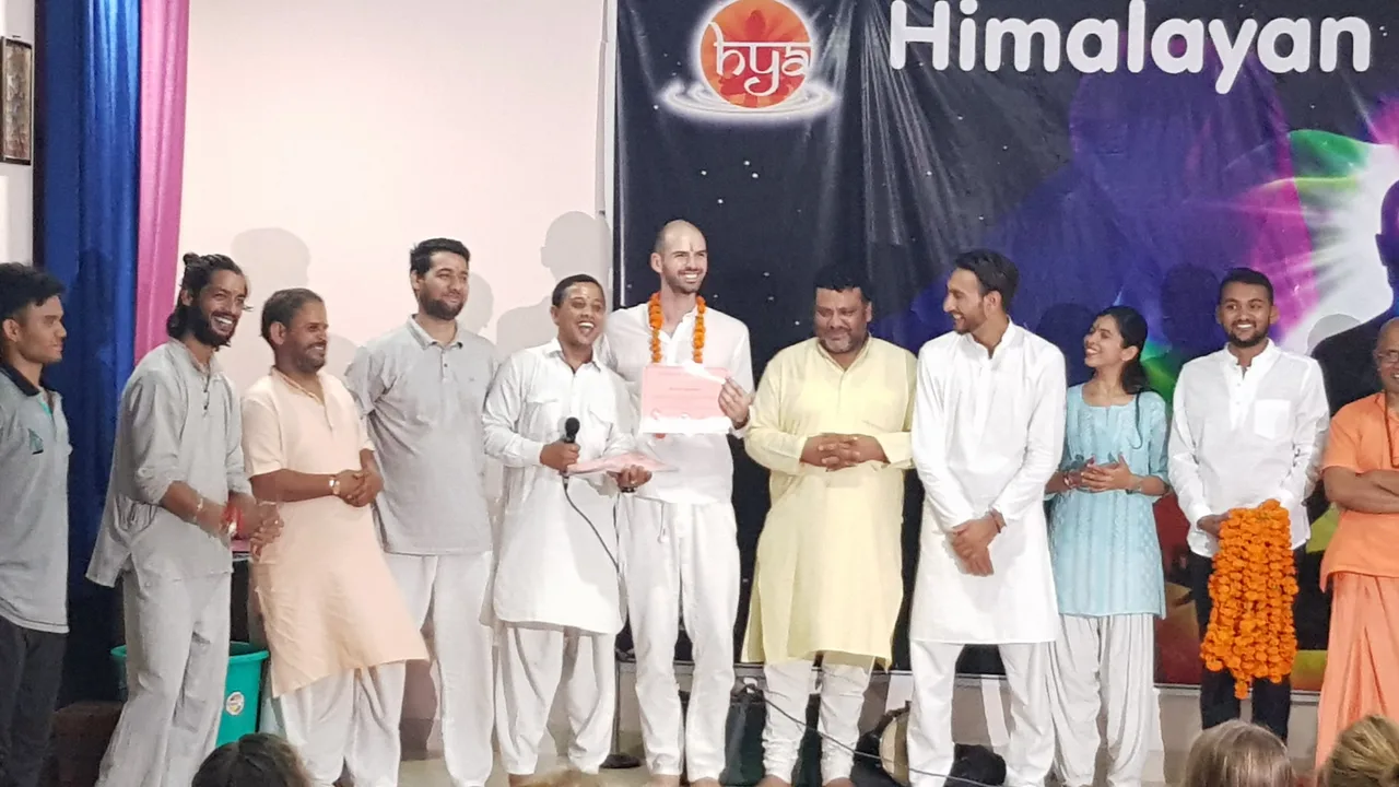 A yoga teacher-training ceremony with participants and teachers on stage